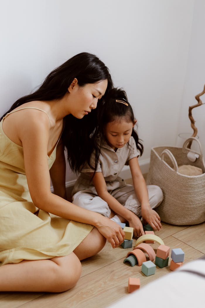 Mother and daughter enjoy quality time playing with colorful wooden blocks at home.