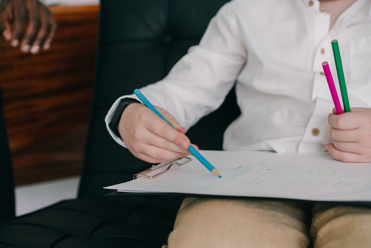 A child focused on drawing with colored pencils in an educational setting.